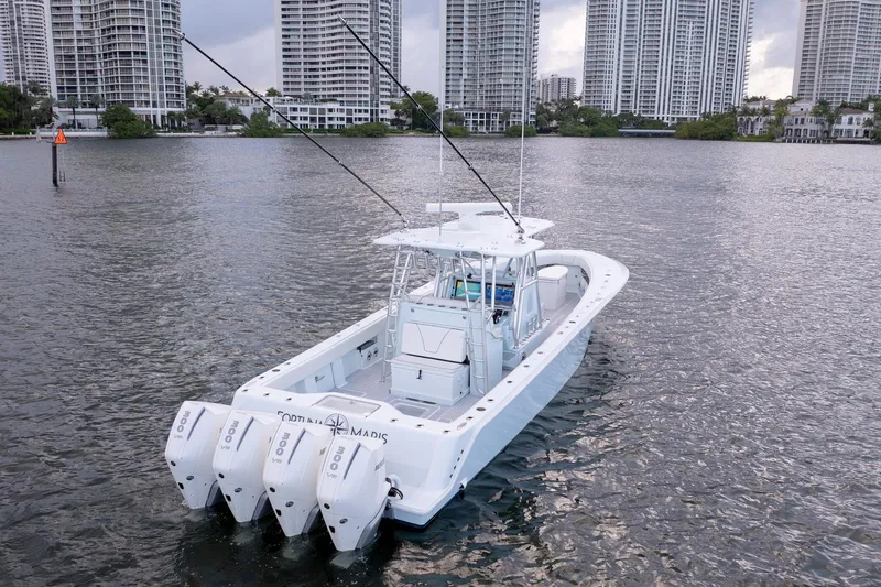 Slide: The Image of 2023 SeaVee 390Z boat with triple engines on a calm waterway, city skyline in background. - 9