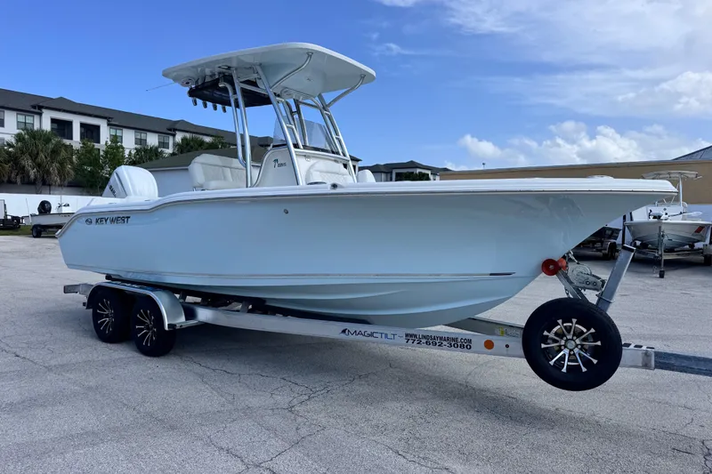Slide: The Image of 2026 Key West 239 FS boat on trailer, parked outdoors under a partly cloudy sky. - 6