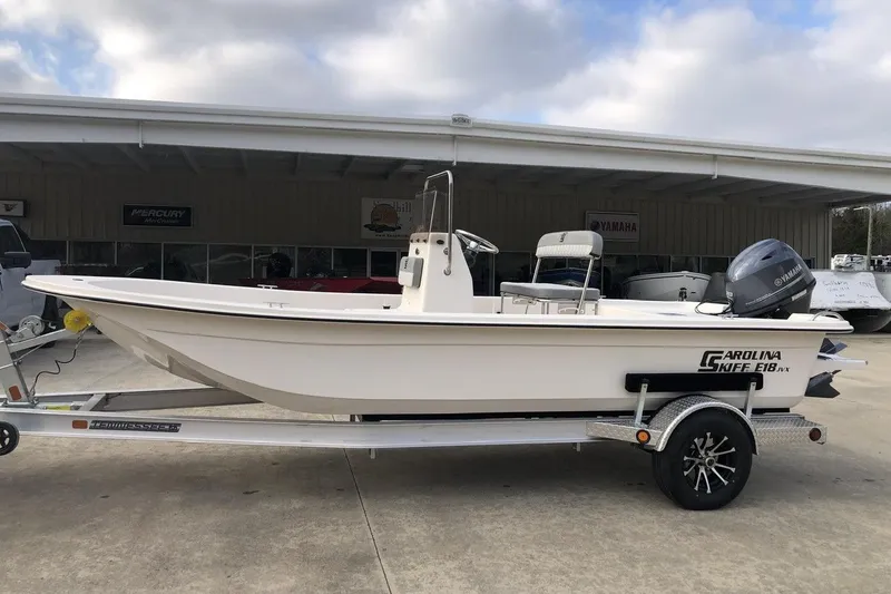 The Image of 2025 Carolina Skiff E18 JVX CC boat on trailer, parked outdoors. - 0