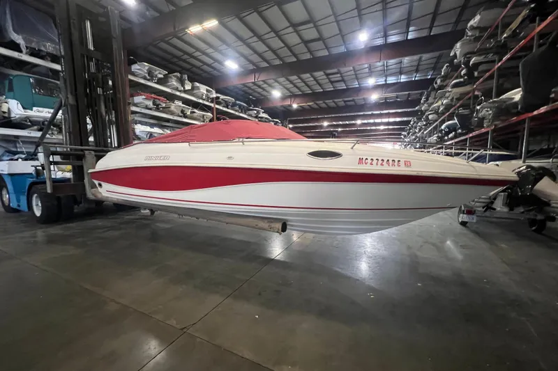 The Image of 1996 Rinker 232 Captiva Cuddy boat in storage, featuring red and white design. - 1