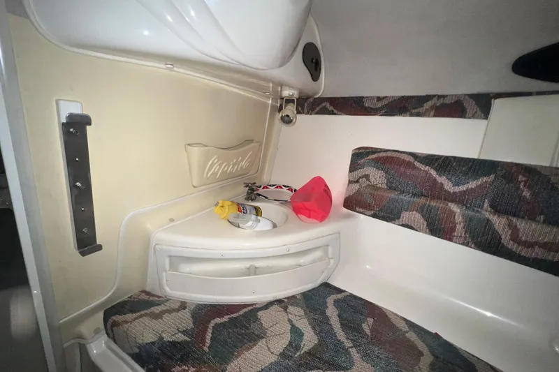 Slide: The Image of Interior of a 1996 Rinker 232 Captiva Cuddy boat with patterned seating and storage. - 14