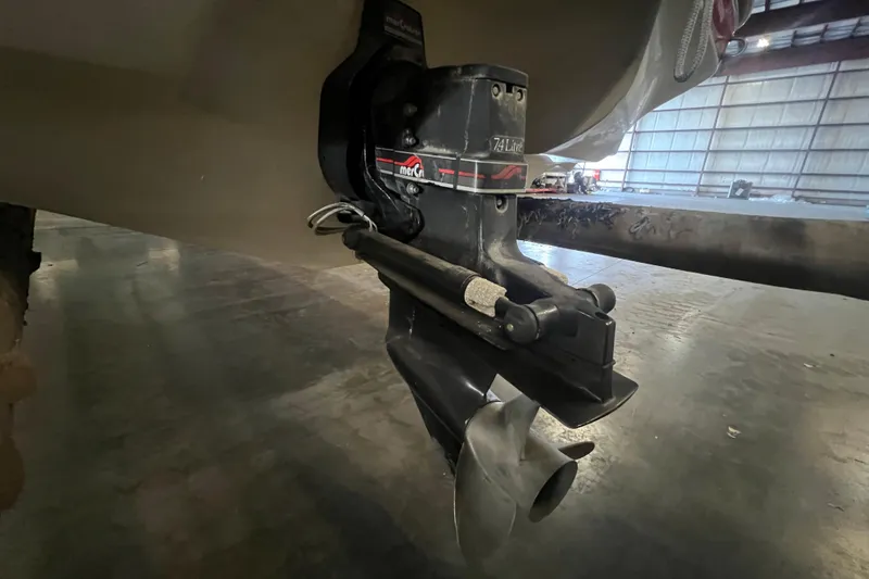 Slide: The Image of 1996 Rinker 232 Captiva Cuddy boat engine and propeller in a warehouse setting. - 15