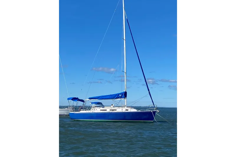 Slide: The Image of 1998 J Boats J/32 sailboat with blue covers on calm water under clear sky. - 10