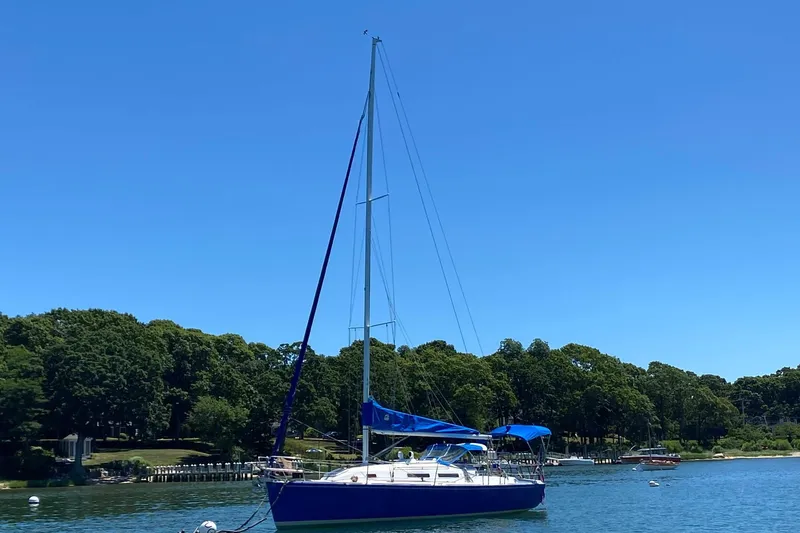 Slide: The Image of 1998 J Boats J/32 sailboat on calm water, surrounded by lush greenery. - 11