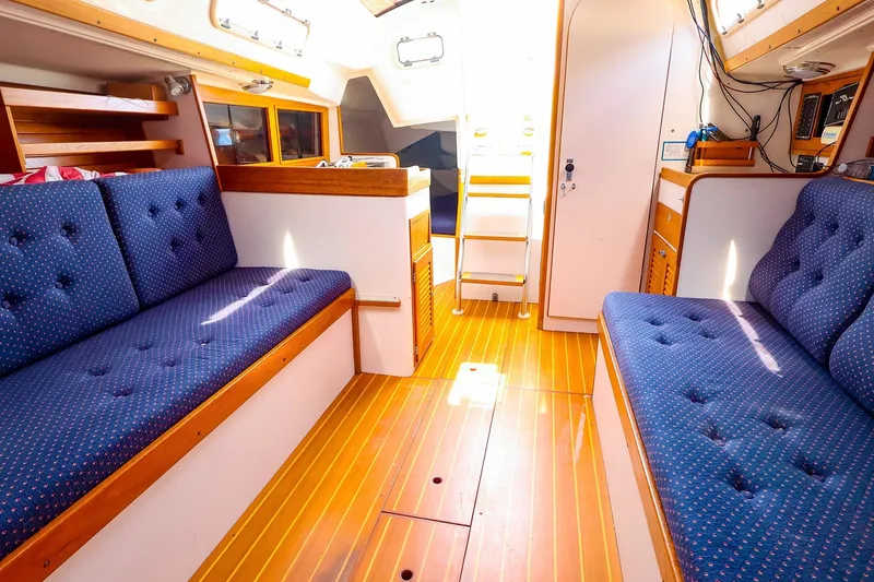 Slide: The Image of Interior of a 1998 J Boats J/32 sailboat with blue cushioned seating and wooden flooring. - 27