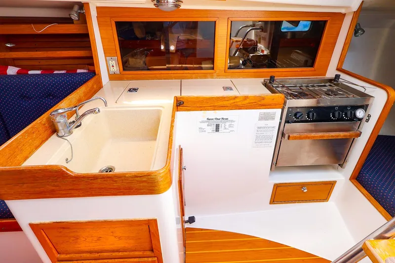 Slide: The Image of 1998 J Boats J/32 yacht galley with sink, stove, and wooden cabinetry. - 28