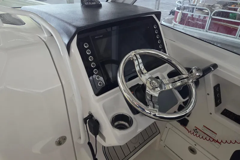 Slide: The Image of 2019 Edgewater 262CX Crossover boat helm with steering wheel and control panel. - 13