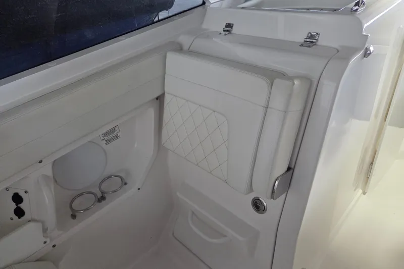 Slide: The Image of 2019 Edgewater 262CX Crossover boat interior with white cushioned seating and storage compartment. - 14
