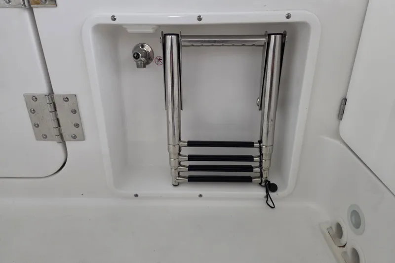 Slide: The Image of 2019 Edgewater 262CX Crossover boat ladder compartment with stainless steel retractable ladder. - 18
