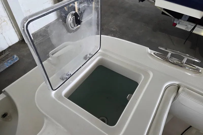 Slide: The Image of Open storage compartment on 2019 Edgewater 262CX Crossover boat, featuring a transparent lid. - 19