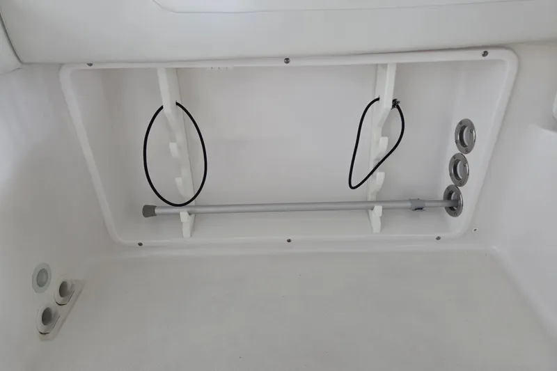 Slide: The Image of Storage compartment in 2019 Edgewater 262CX Crossover boat, featuring rod holders and drainage outlets. - 20