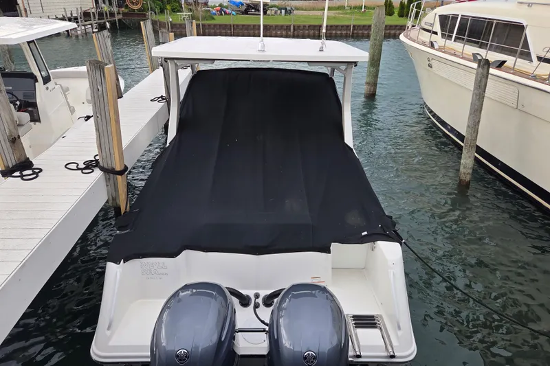 Slide: The Image of 2019 Edgewater 262CX Crossover boat docked with cover and twin outboard motors. - 3