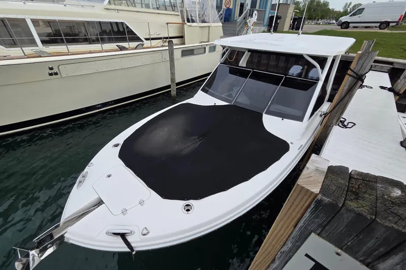Slide: The Image of 2019 Edgewater 262CX Crossover boat docked with black cover, marina background. - 4