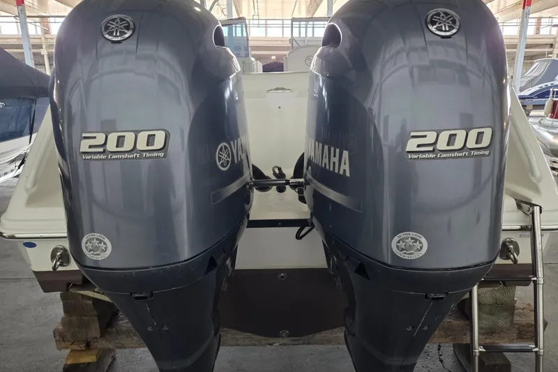 Slide: The Image of Twin Yamaha 200 engines on a 2019 Edgewater 262CX Crossover boat in a marina. - 6