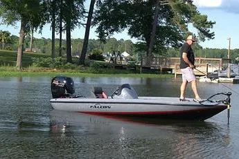 Slide: The Image of 2025 Falcon Boats 18 Freedom on a serene lake with a person fishing. - 2