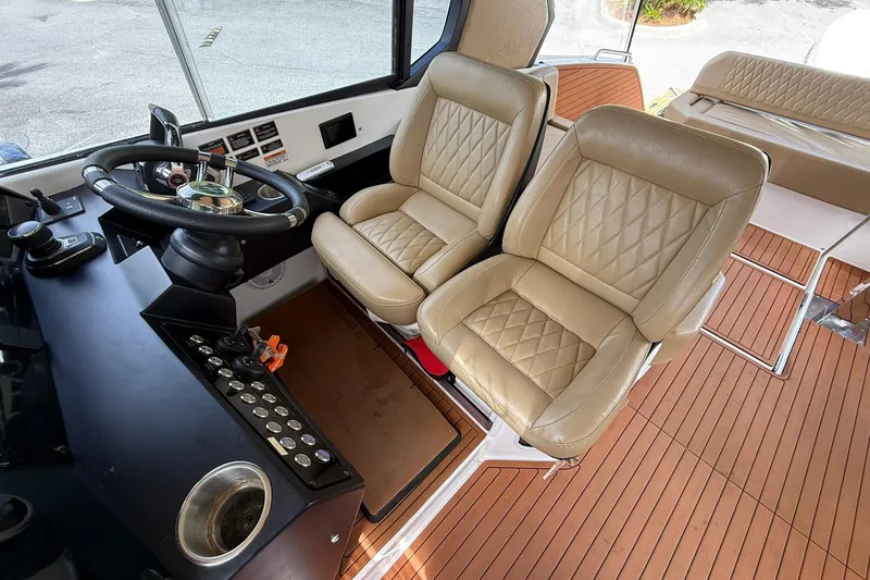 Slide: The Image of 2024 Hanover 387 boat cockpit with beige leather seats and modern steering controls. - 14