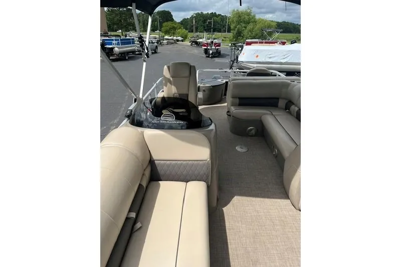 Slide: The Image of 2023 SUNTRACKER Fishing Barge 20 interior with beige seating and steering console. - 5