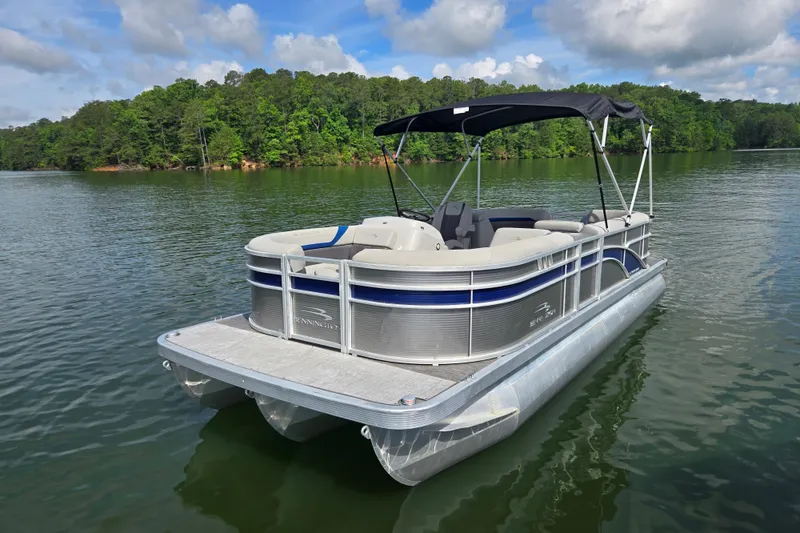 The Image of 2023 Bennington 22 SSR pontoon boat on a serene lake with lush green trees. - 1