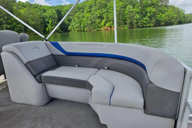 Slide: The Image of 2023 Bennington 22 SSR pontoon boat interior with plush seating by a scenic lake. - 13