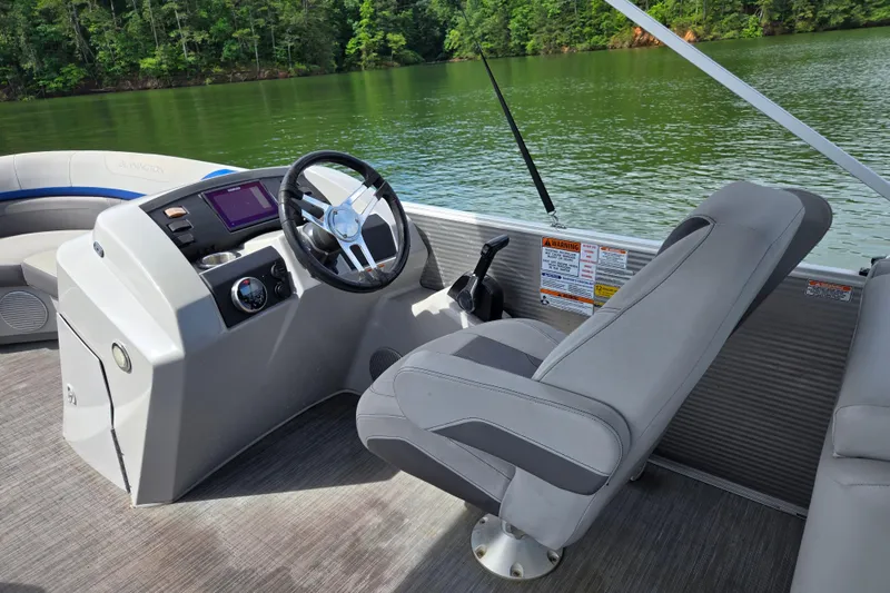 Slide: The Image of 2023 Bennington 22 SSR boat interior with steering wheel and control panel on a lake. - 15