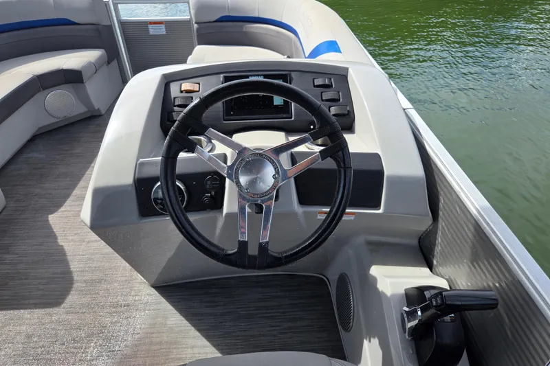 Slide: The Image of 2023 Bennington 22 SSR boat steering console with modern controls on a calm lake. - 17