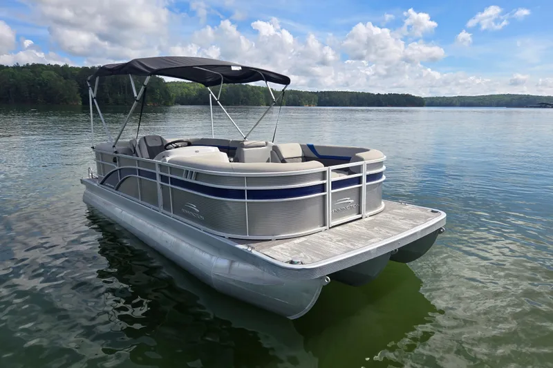 Slide: The Image of 2023 Bennington 22 SSR pontoon boat on a serene lake under a blue sky. - 3