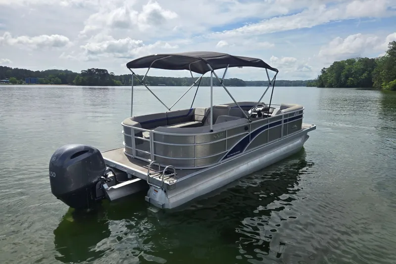 Slide: The Image of 2023 Bennington 22 SSR pontoon boat on a serene lake under a cloudy sky. - 5