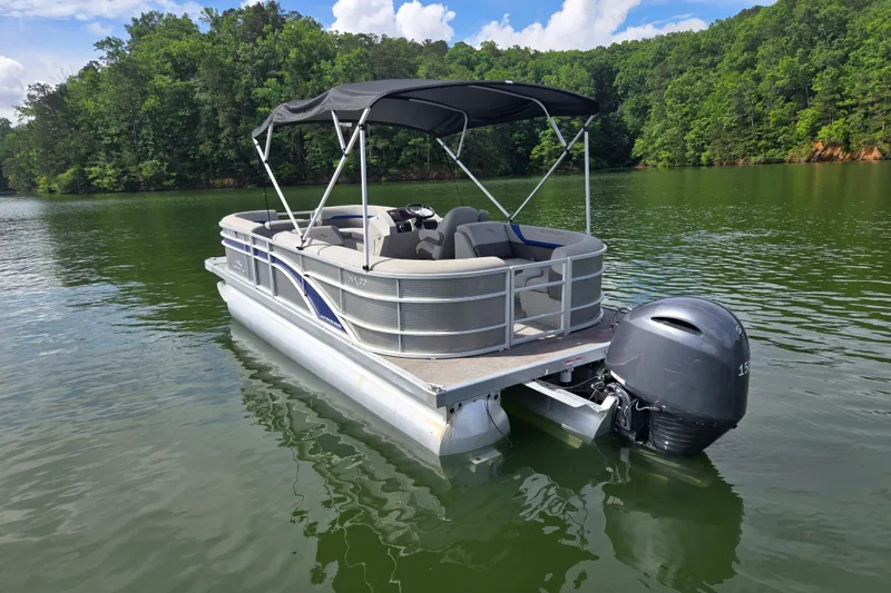 Slide: The Image of 2023 Bennington 22 SSR pontoon boat on a serene lake with lush green surroundings. - 7