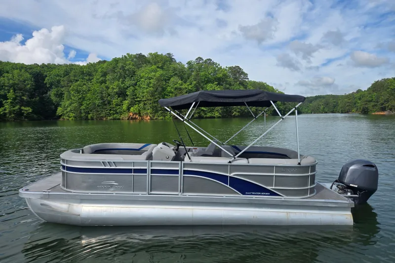 Slide: The Image of 2023 Bennington 22 SSR pontoon boat on a scenic lake with lush green trees. - 8