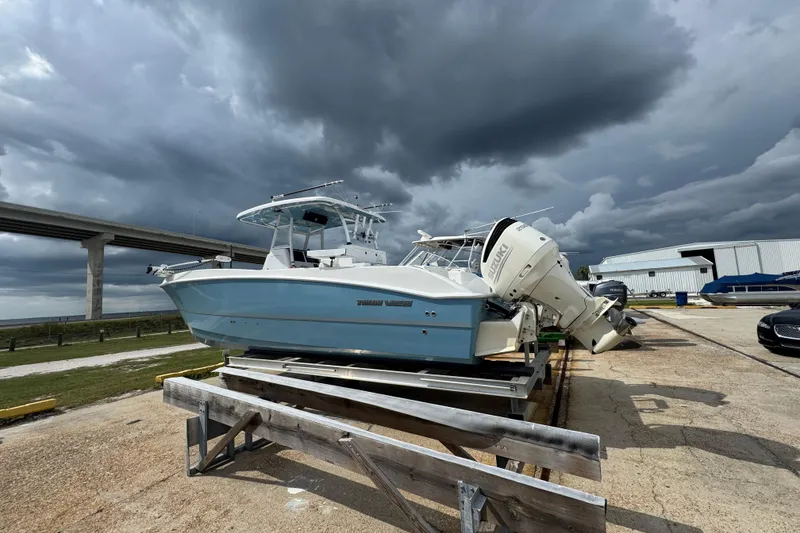 Slide: The Image of 2021 Twin Vee 280 CC GF boat on trailer under stormy skies near a bridge. - 21