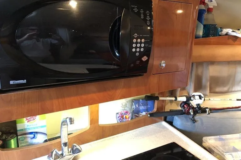 Slide: The Image of 2006 Four Winns 258 Vista boat interior with microwave, sink, and fishing rod. - 10