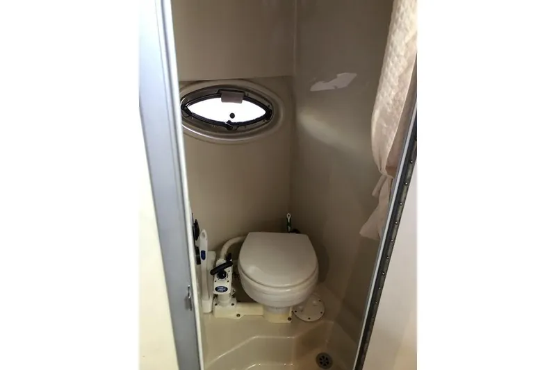Slide: The Image of 2006 Four Winns 258 Vista boat bathroom with compact toilet and porthole window. - 13