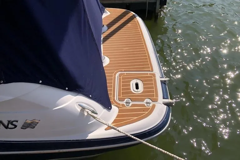 Slide: The Image of 2006 Four Winns 258 Vista boat with teak deck, docked on shimmering water. - 14