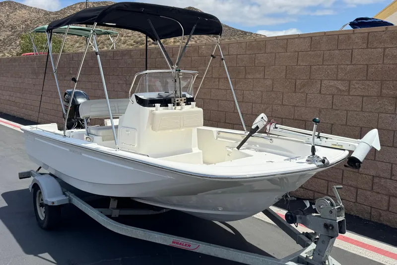 Slide: The Image of 2019 Boston Whaler 150 Montauk boat on trailer with canopy, parked outdoors. - 1