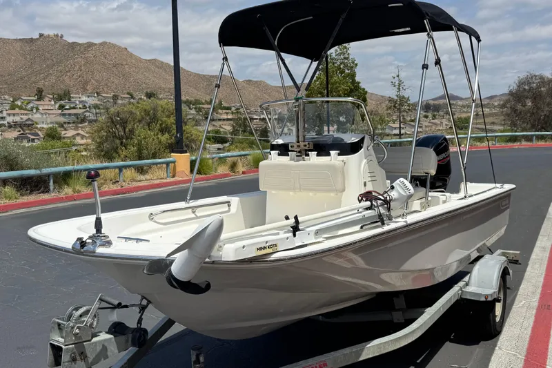 Slide: The Image of 2019 Boston Whaler 150 Montauk boat on trailer, parked outdoors with scenic background. - 3