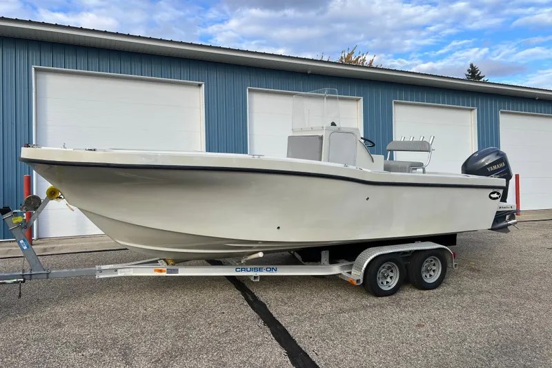 Slide: The Image of 2010 Dusky 256 Center Console boat on trailer, parked near blue building. - 1