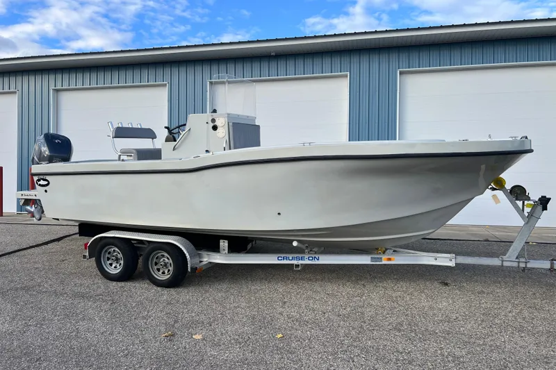 Slide: The Image of 2010 Dusky 256 Center Console boat on trailer, parked outside a garage. - 2