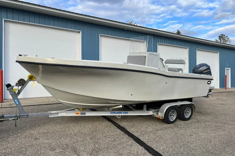 Slide: The Image of 2010 Dusky 256 Center Console boat on trailer, parked near blue building. - 3