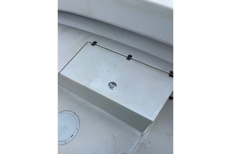 Slide: The Image of 2010 Dusky 256 Center Console boat storage compartment with latch, white interior. - 40