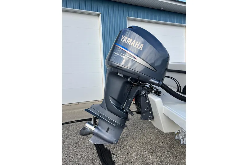 Slide: The Image of Yamaha outboard motor on 2010 Dusky 256 Center Console boat, parked near blue building. - 8