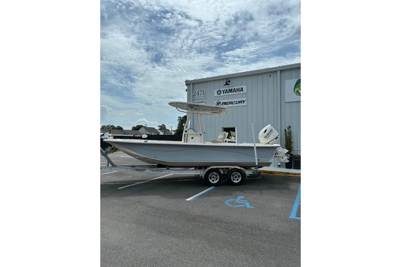 Slide: The Image of 2020 Carolina Skiff 23LS boat on trailer, parked outside dealership with Yamaha and Mercury signage. - 9
