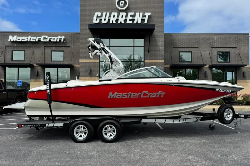 Slide: The Image of 2014 MasterCraft X-35 boat in red, parked on a trailer outside a dealership. - 2