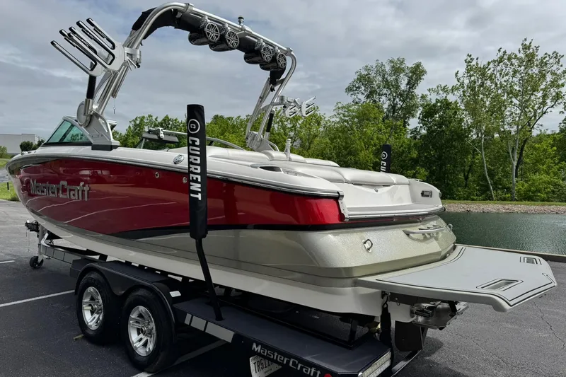 Slide: The Image of 2014 MasterCraft X-35 boat with red and white design on a trailer by a lake. - 5