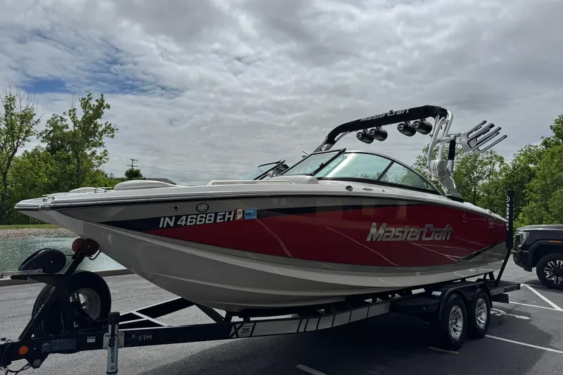 Slide: The Image of 2014 MasterCraft X-35 boat on trailer, parked outdoors under cloudy sky. - 7