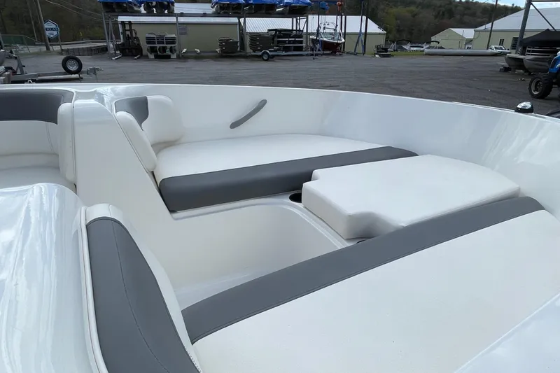 Slide: The Image of 2019 Bayliner Element E16 boat interior with white and gray seating in a marina setting. - 18