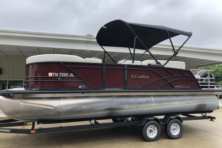 The Image of 2022 Sylvan Mirage X X3 CLZ pontoon boat on trailer, under cloudy sky. - 0