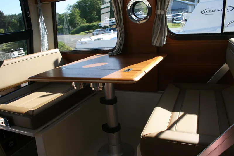 Slide: The Image of 2024 Ranger Tugs R-25 interior with dining table and cushioned seating. - 12