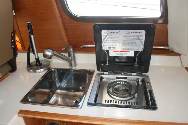 Slide: The Image of 2024 Ranger Tugs R-25 galley with stainless steel sink and Kenyon stove. - 13