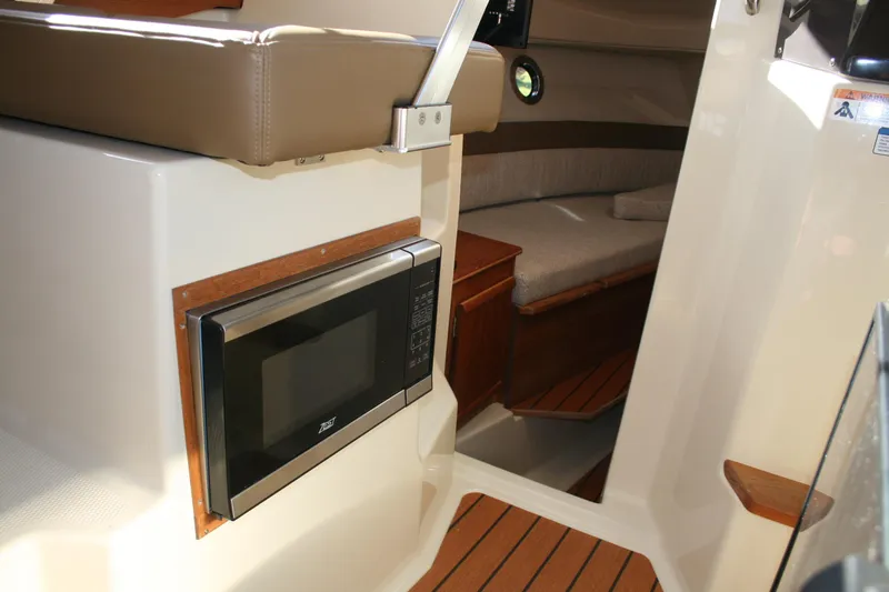 Slide: The Image of 2024 Ranger Tugs R-25 interior with microwave and cozy cabin seating. - 16