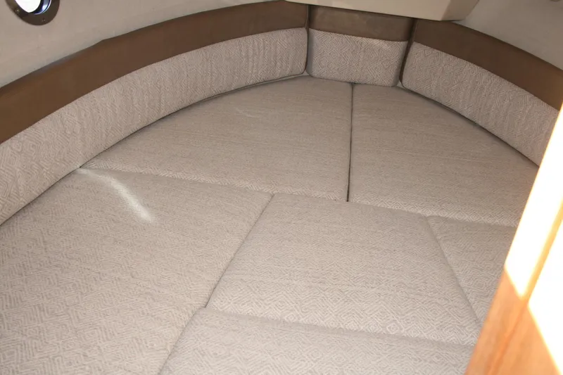 Slide: The Image of 2024 Ranger Tugs R-25 interior cabin with beige cushioned seating. - 17